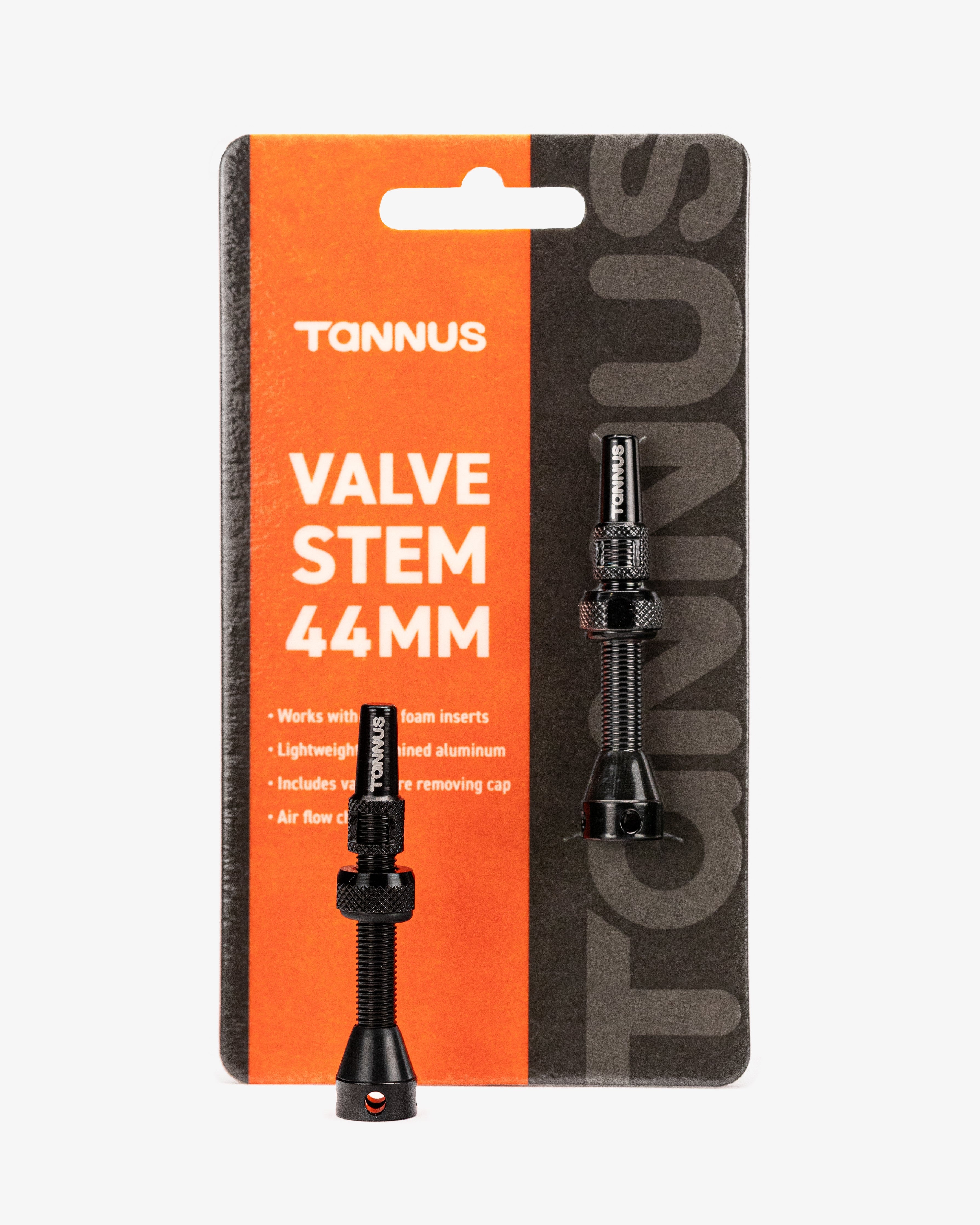 A black Tannus valve stem inserts in their original retail blister packaging, featuring a bright orange and dark gray card with white text.